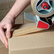 a man sealing a cardboard box with brown paper tape