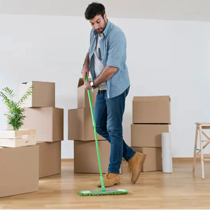 man cleaning a wooden floor in an empty house surrounded by moving boxes