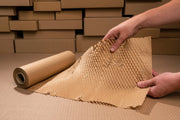 a roll of grip paperflex honeycomb paper being held in front of some cardboard boxes