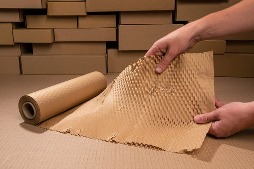 a roll of grip paperflex honeycomb paper being held in front of some cardboard boxes