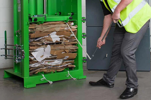 Detail image of cardboard in a Cardboard Baler being wrapped with strapping in a warehouse environment