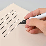 Hand holding a black marker drawing lines on a sheet of paper