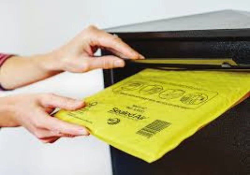 a woman's hand placing a Sealed Air Mail Lite padded envelope in a postbox on a white background