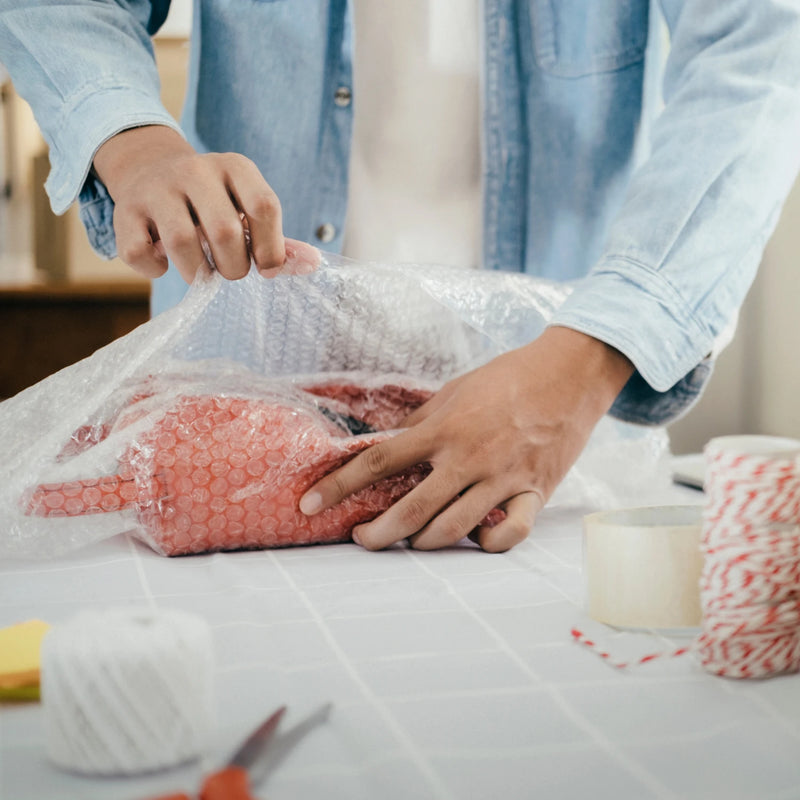 Man wrapping a parcel using bubble wrap