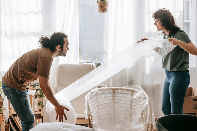 Couple wrapping furniture with bubble wrap
