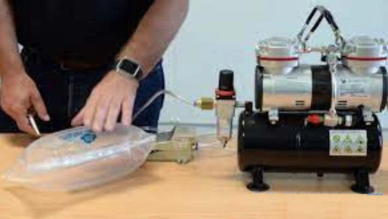 person using an air compressor to inflate Bubl air cushioning packaging at a desk on a plain background