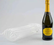 a bottle of prosecco beside an inflated Bubl Single air cushioning pod on a plain background