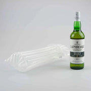 a bottle of whiskey beside an inflated Bubl Single air cushioning pod on a plain background