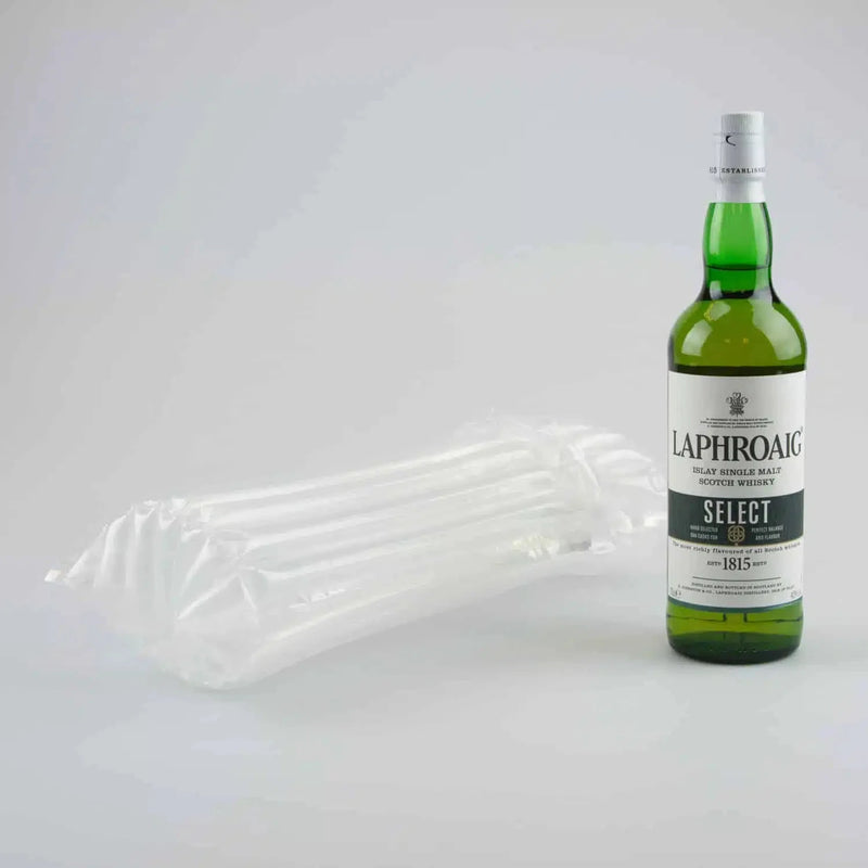 a bottle of whiskey beside an inflated Bubl Single air cushioning pod on a plain background