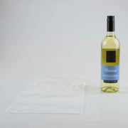 a bottle of white wine beside an uninflated Bubl Single air cushioning pod on a plain background