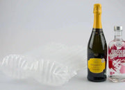 Two bottles of Prosecco and Vodka beside an inflated Bubl Double air cushioning pod on a plain background