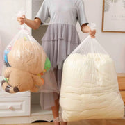 woman holding two large clear bedding bags filled with a duvet and childrens toys