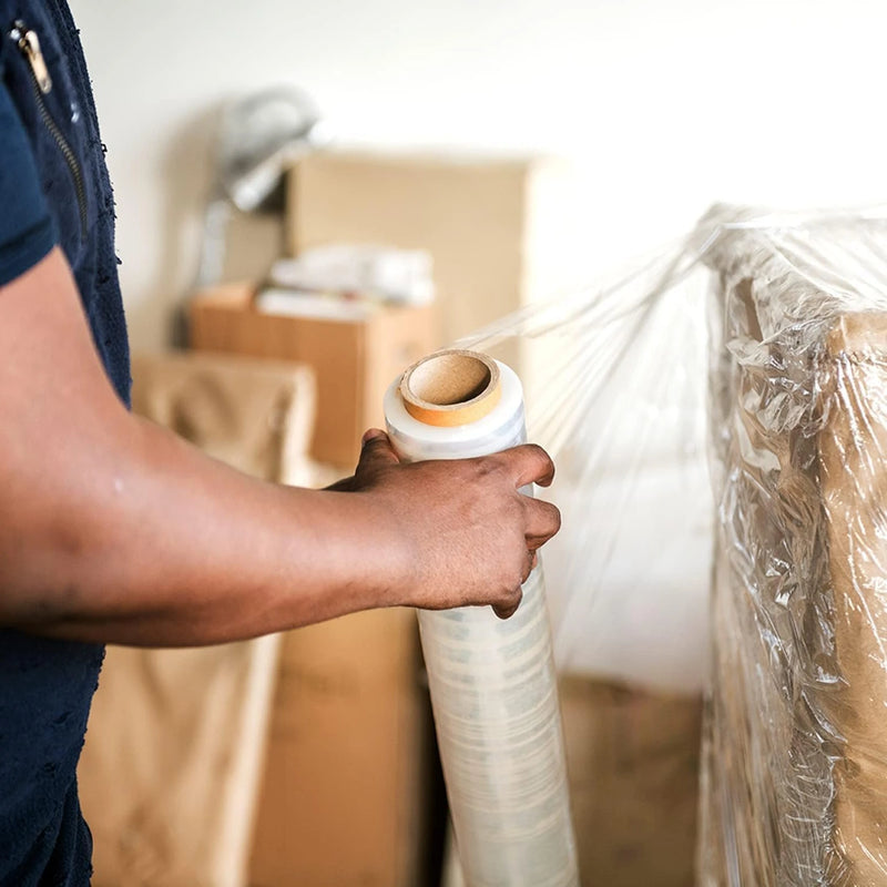 Man wrapping a pallet with clear pallet wrap in an industrial setting