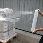Person wrapping a pallet with clear pallet wrap in a warehouse setting