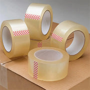 five rolls of clear sealing tape placed on a cardboard box on a neutral background