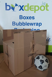 a large cardboard box on a table beside a football for size perspective in front of Box Depot advertising