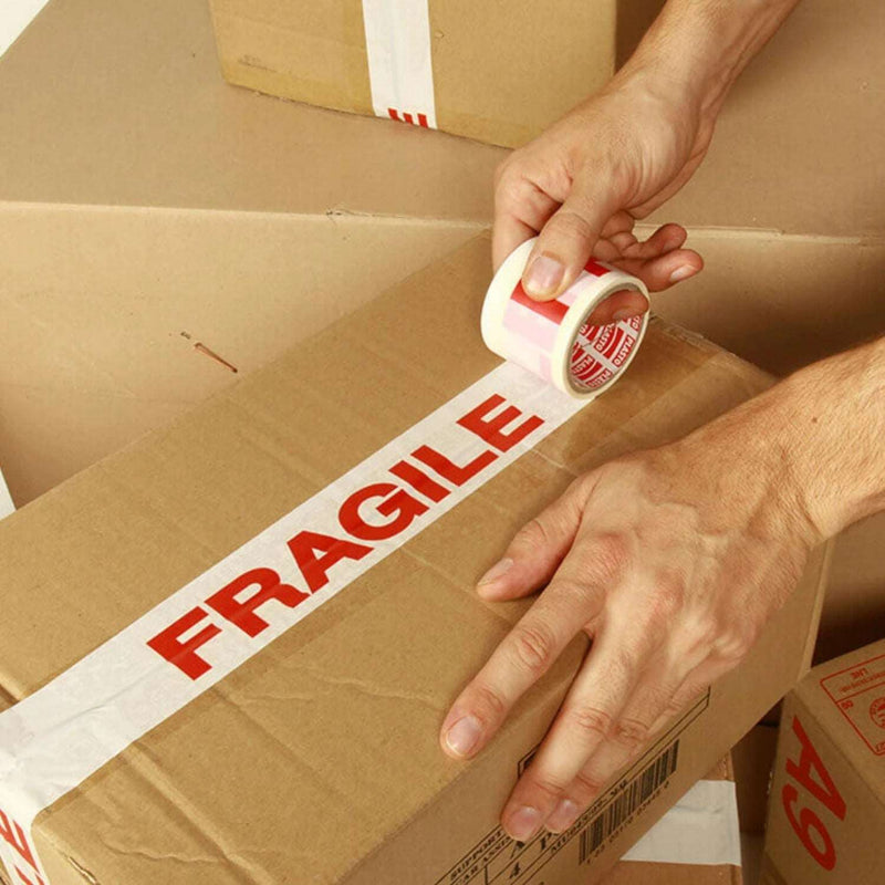 A man sealing a cardboard box by hand with fragile tape