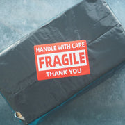 fragile label on a parcel wrapped in a grey mailing bag on a grey background