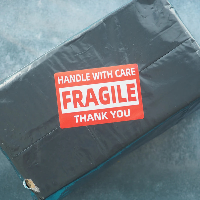 fragile label on a parcel wrapped in a grey mailing bag on a grey background