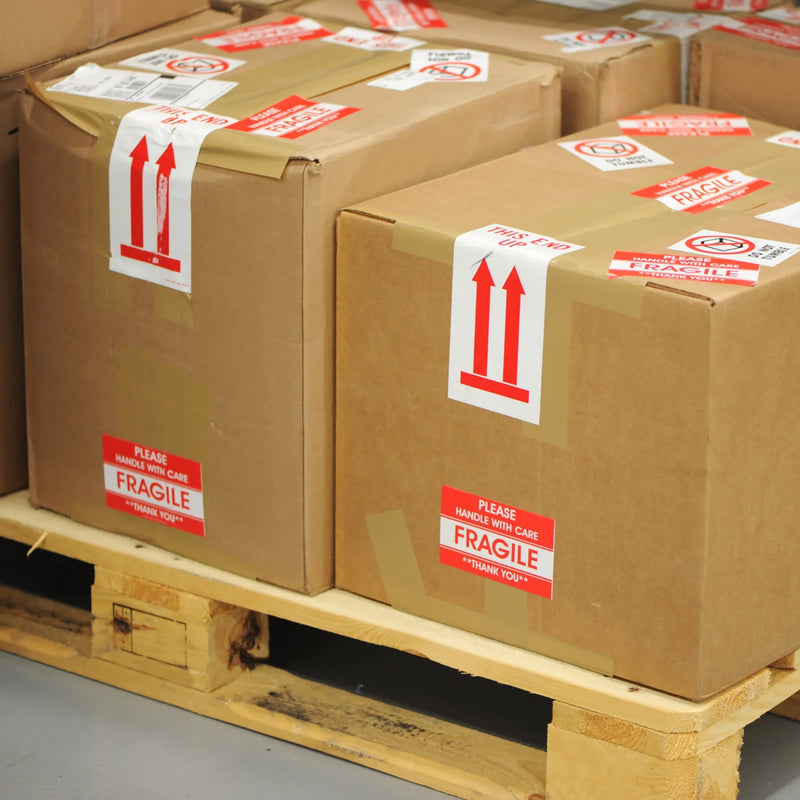 various fragile labels on brown cardboard boxes that are on a wooden pallet