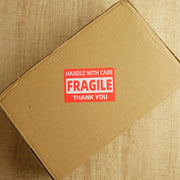fragile label on a brown cardboard postal box on a wooden desk