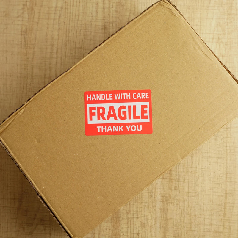 fragile label on a brown cardboard postal box on a wooden desk