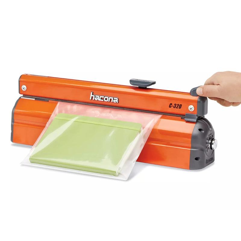 Hand using a Hacona C320 Heat Sealer to seal a green product in a clear bag on a white background