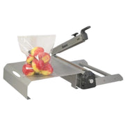 Hacona CI320 inox Heat Sealer with an empty bag roller and a bag of fruit sealed in a bag that is sitting on the modular table on a white background