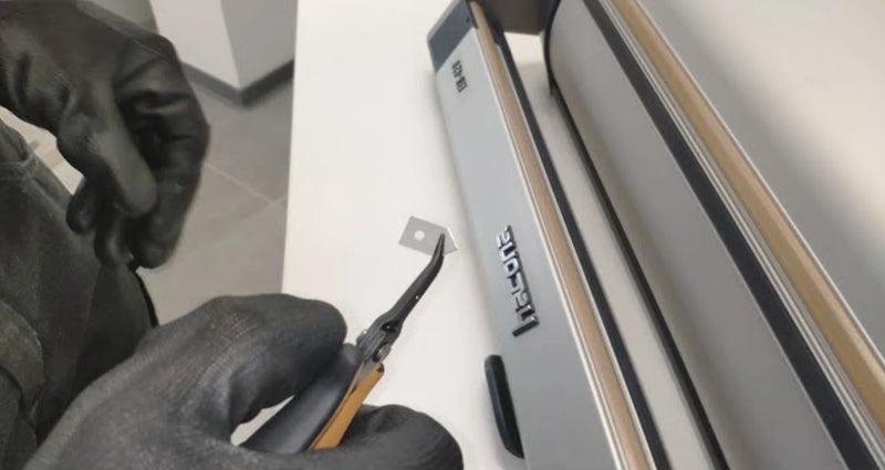 A person replacing a blade on a Hacona Heat Sealer in a warehouse/work environment