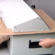 Clos up of a hand feeding cardboard into a Kobra FlexPack Desktop Cardboard Shredder