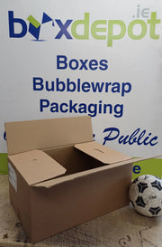 a medium single walled cardboard box beside a football in front of Box Depot advertisement