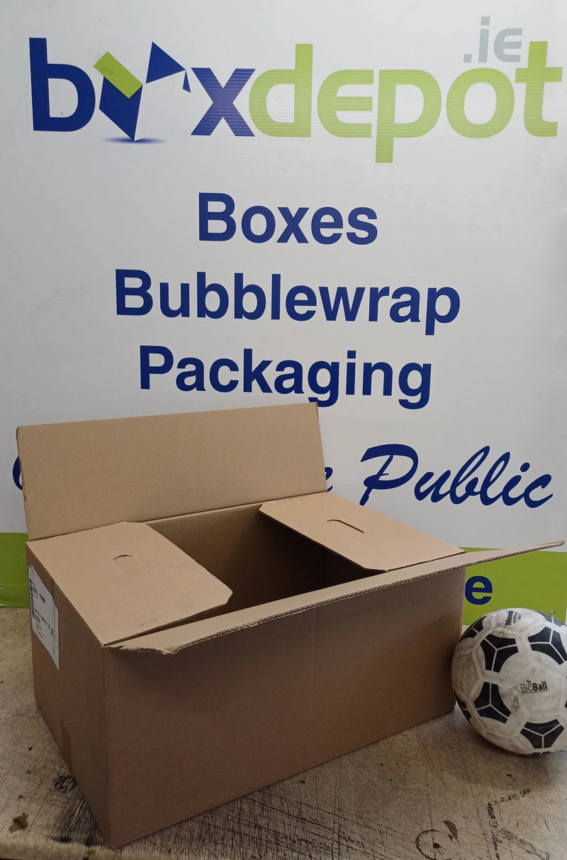a medium single walled cardboard box beside a football in front of Box Depot advertisement