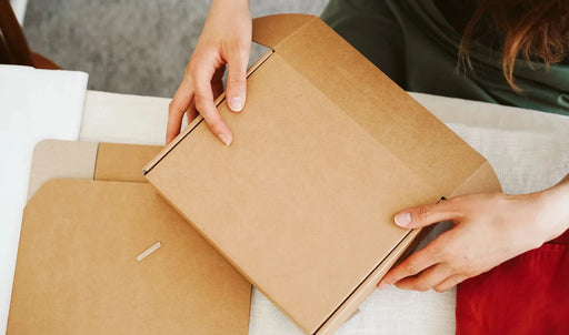Person at a desk opening a postal diecut cardboard box