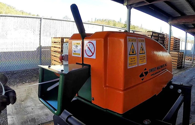 closeup of a Sweed CE450DDX Strapping Chopper being fed with metal pallet strapping outdoors in a warehouse environment