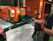 man feeding a Sweed CE450DDX Strapping Chopper with lengths of  plastic pallet strapping in a warehouse