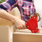 a woman using a tape gun to apply brown tape to a cardboard box