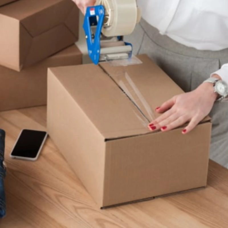 closeup of a woman sealing a cardboard box with sealing tape on a table