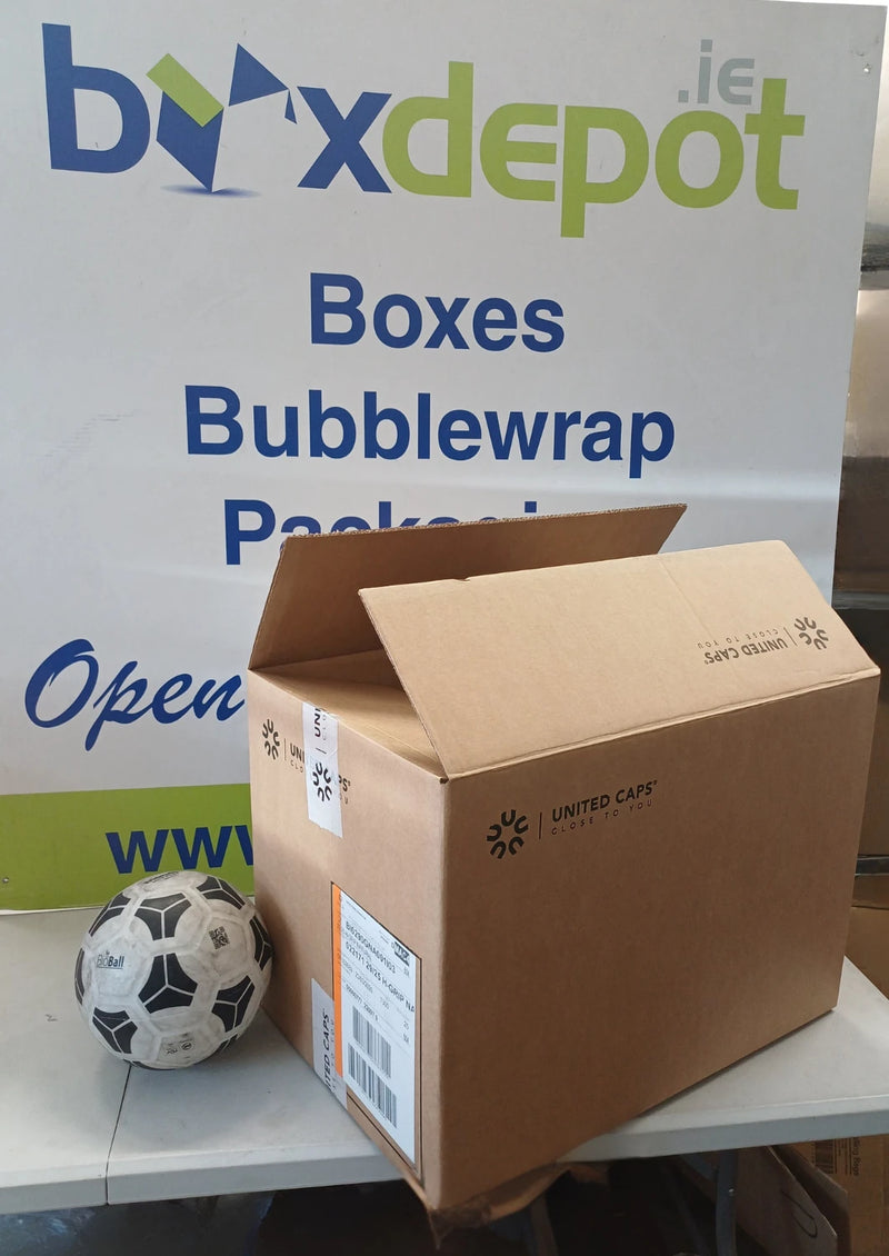 A brown cardboard shipping box placed in front of Box Depot advertisng and a soccer ball on a table