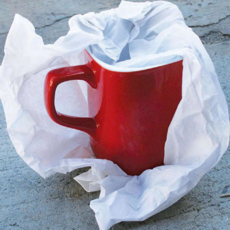 a sheet of acid free tissue paper wrapped around a red mug on a slate background