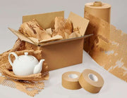 an unrolled roll of Grip Paperflex honeycomb paper beside a cardboard box filled with items wrapped in honeycomb paper and a teapot nestled in honeycomb paper