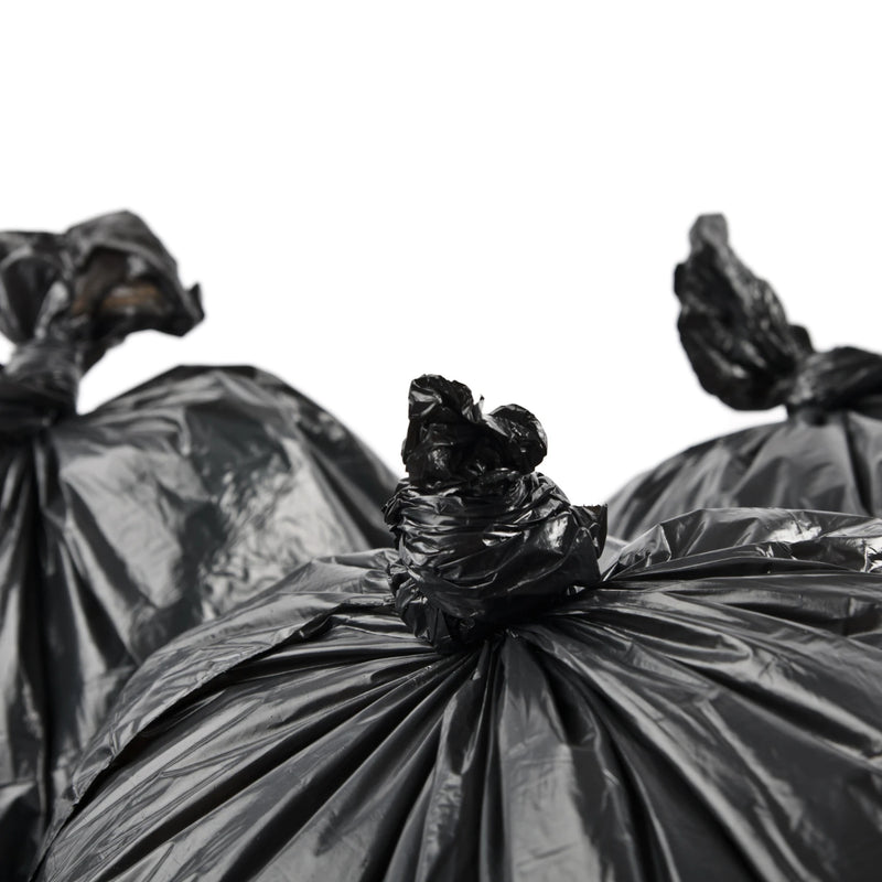 closeup of three black bin bags that have been knotted closed on a white background