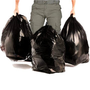 Three black refuse bags held by a person wearing green pants on a white background