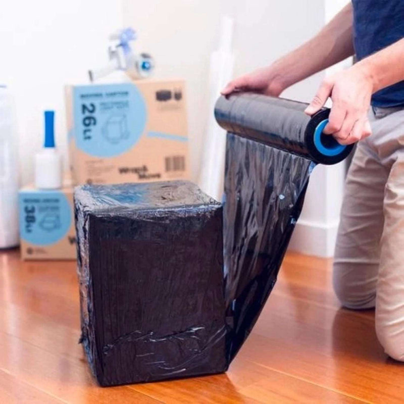 Man in a home environment wrapping a parcel in black pallet wrap