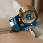 Tape dispenser with brown tape on a cardboard box