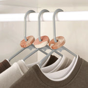 Set of three hangers with cedar moth repellent rings on a wardrobe rail.