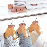 hangars of shirts on a wardrobe rail with cedar moth repellent disks on each hangar as well as cedar moth repellent wooden disks on the shelf above the wardrobe rail