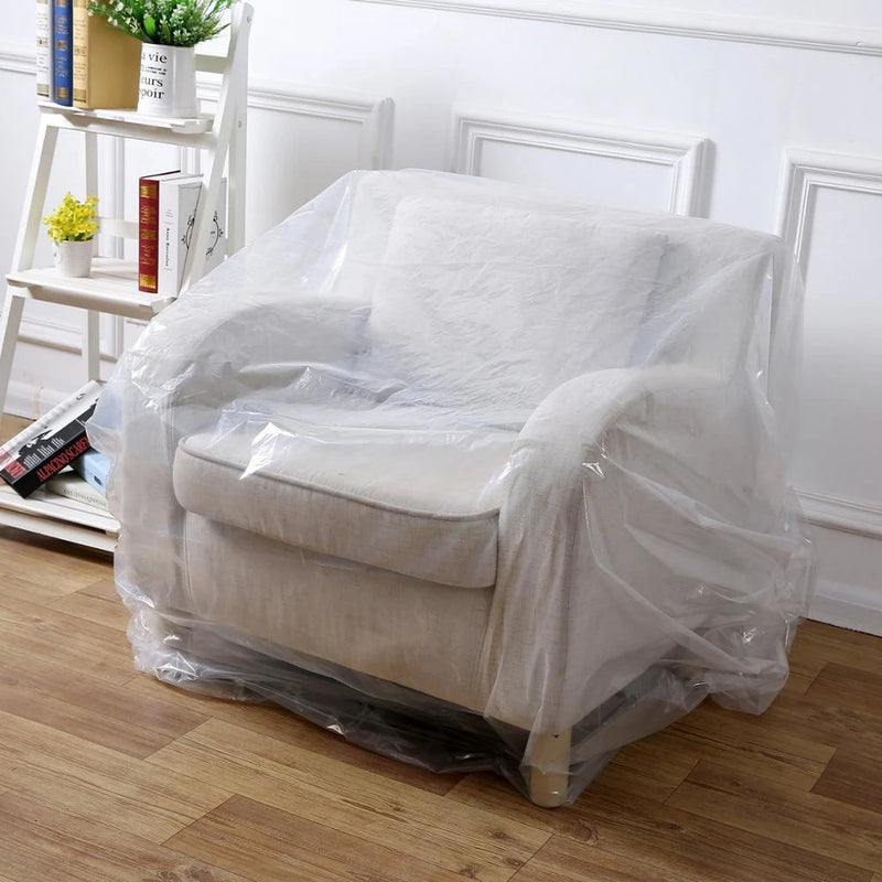 White armchair covered with clear armchair cover bag in a room with wooden floor and white walls.