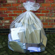 a clear bin bag filled with cardboard in front of a brick wall