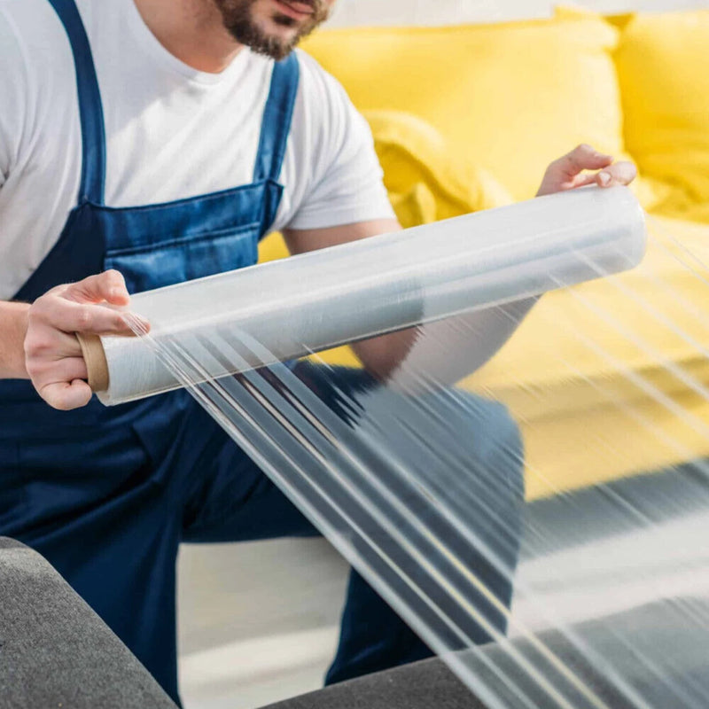 Man in blue overalls wrapping a sofa in clear pallet wrap