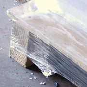 closeup of clear pallet wrap wrapped around the base of a wooden pallet on a concrete floor